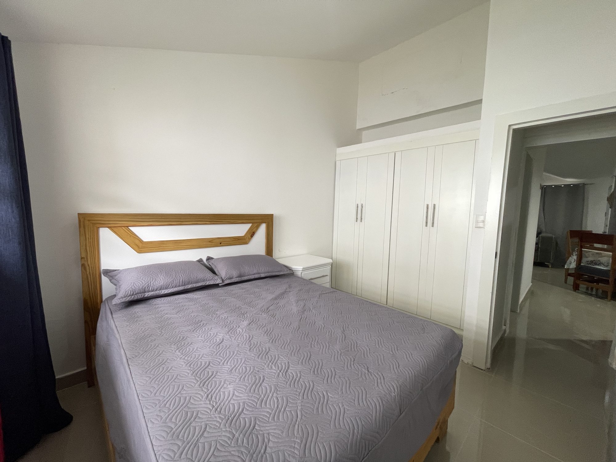 A bedroom with a wooden bed frame and fitted wardrobes