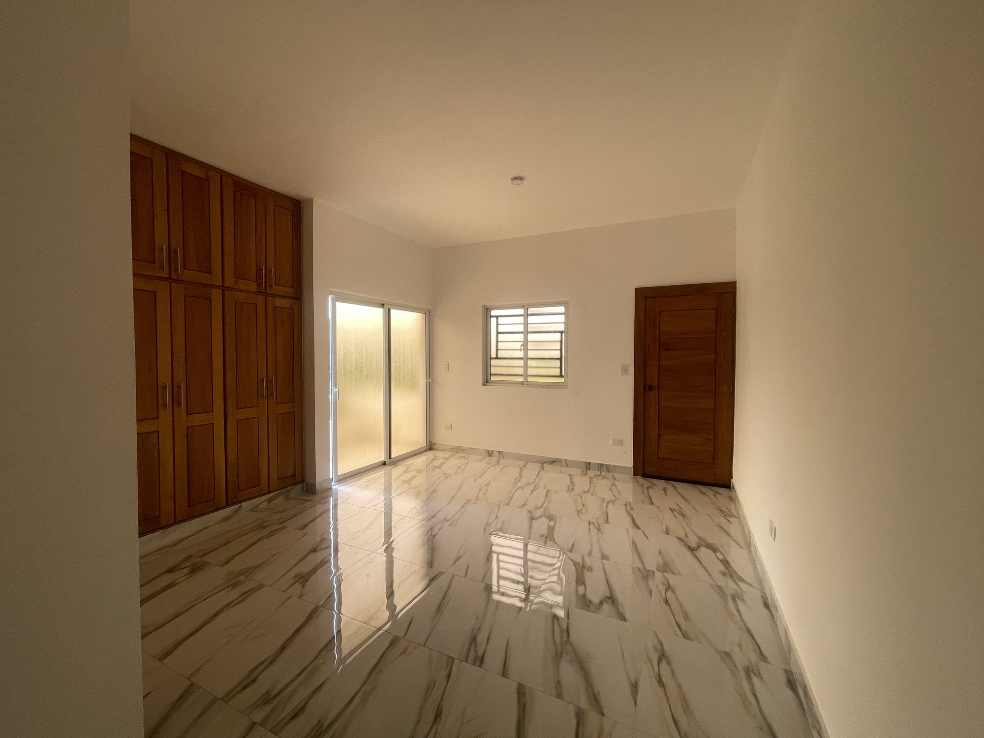 A bedroom with fitted wardrobes and a door to the balcony