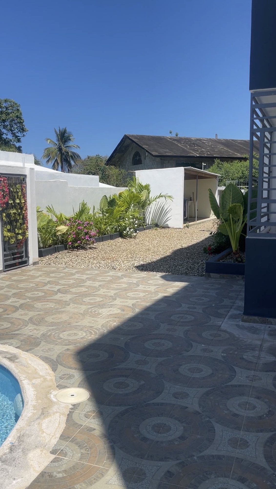 The tiled patio and the garden beside the pool